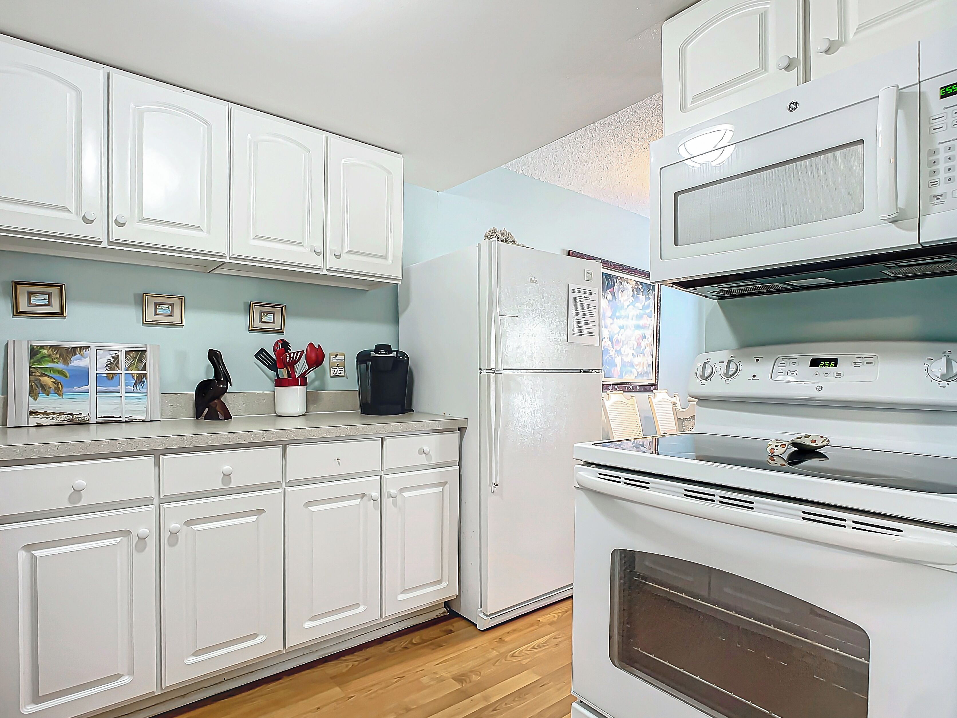 A kitchen with white cabinets, a refrigerator, a coffee maker, and a microwave.