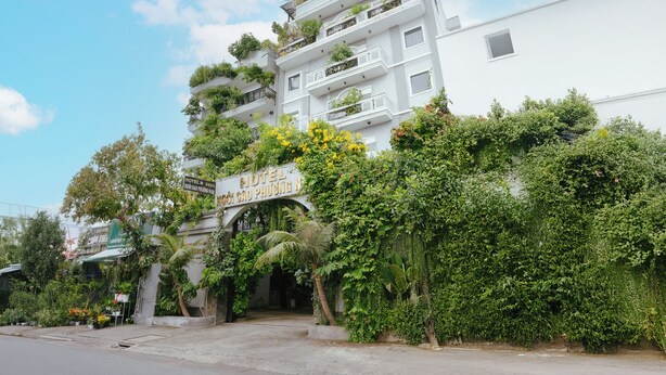 Un hotel de varios pisos con balcones, rodeado de exuberante vegetación y un cielo despejado.