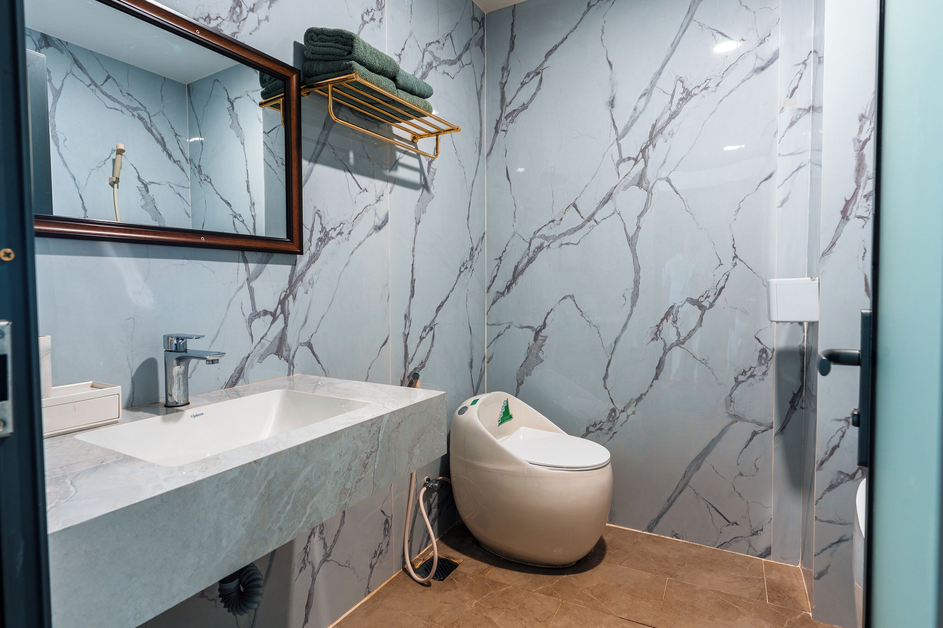 Ein Badezimmer mit Marmorwaschtisch, Toilette und Dusche.