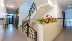 Un interior moderno con una escalera, una recepción adornada con flores y un piso limpio de baldosas.