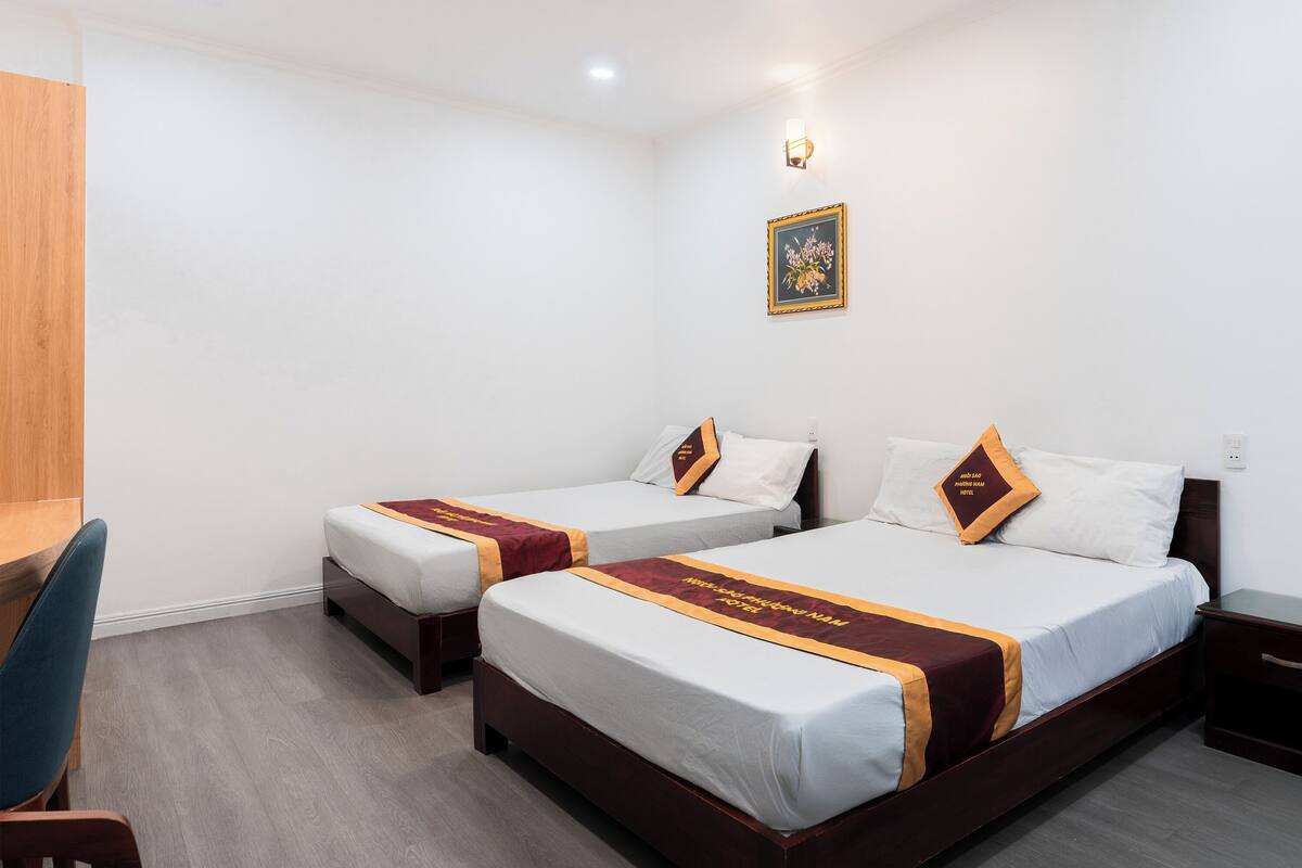 Habitación de hotel con dos camas, un escritorio y una silla.