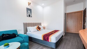 Una habitación de hotel moderna con una cama, un sofá, una mesita y un armario de madera.