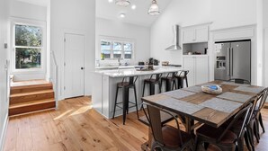 A modern kitchen with a central island, bar stools, and a large refrigerator.