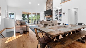 A spacious living area with a wooden dining table, comfortable seating, a fireplace, and a large TV.