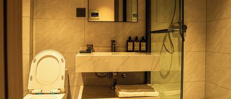 Une salle de bain moderne équipée de toilettes, d’un lavabo et d’une douche à parois de verre.
