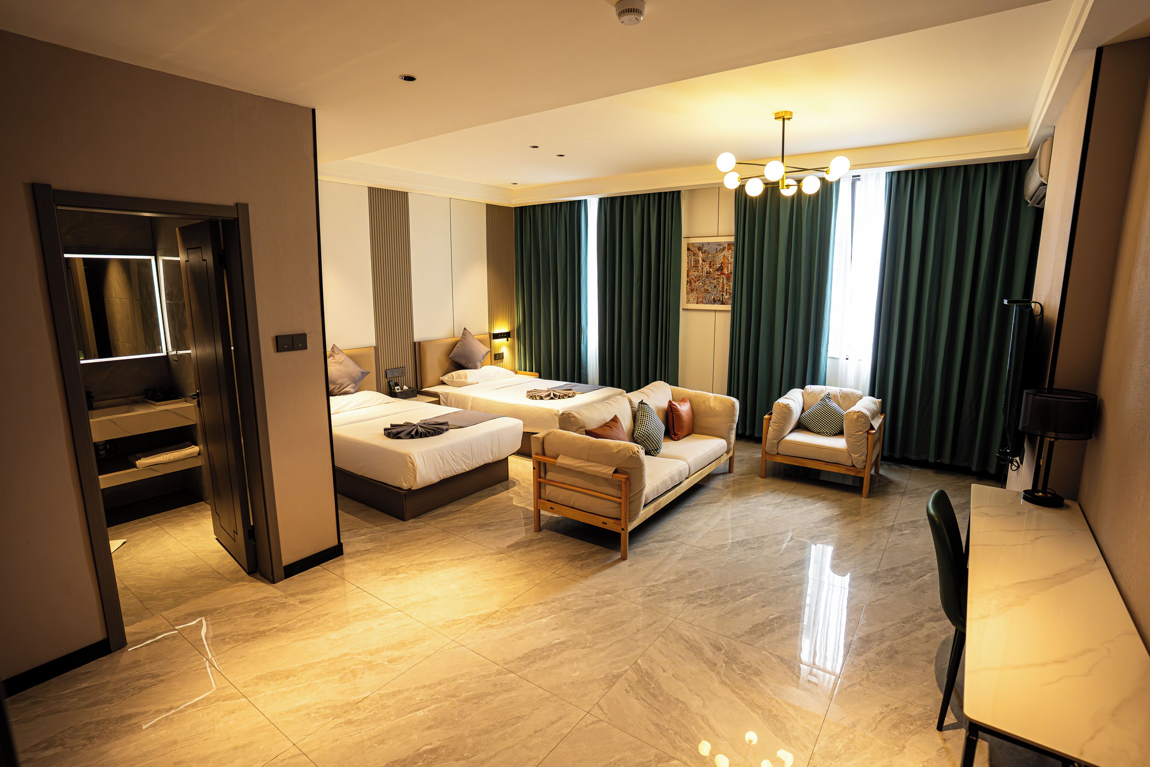 A modern hotel room with a bed, sofa, armchair, and a dining table.