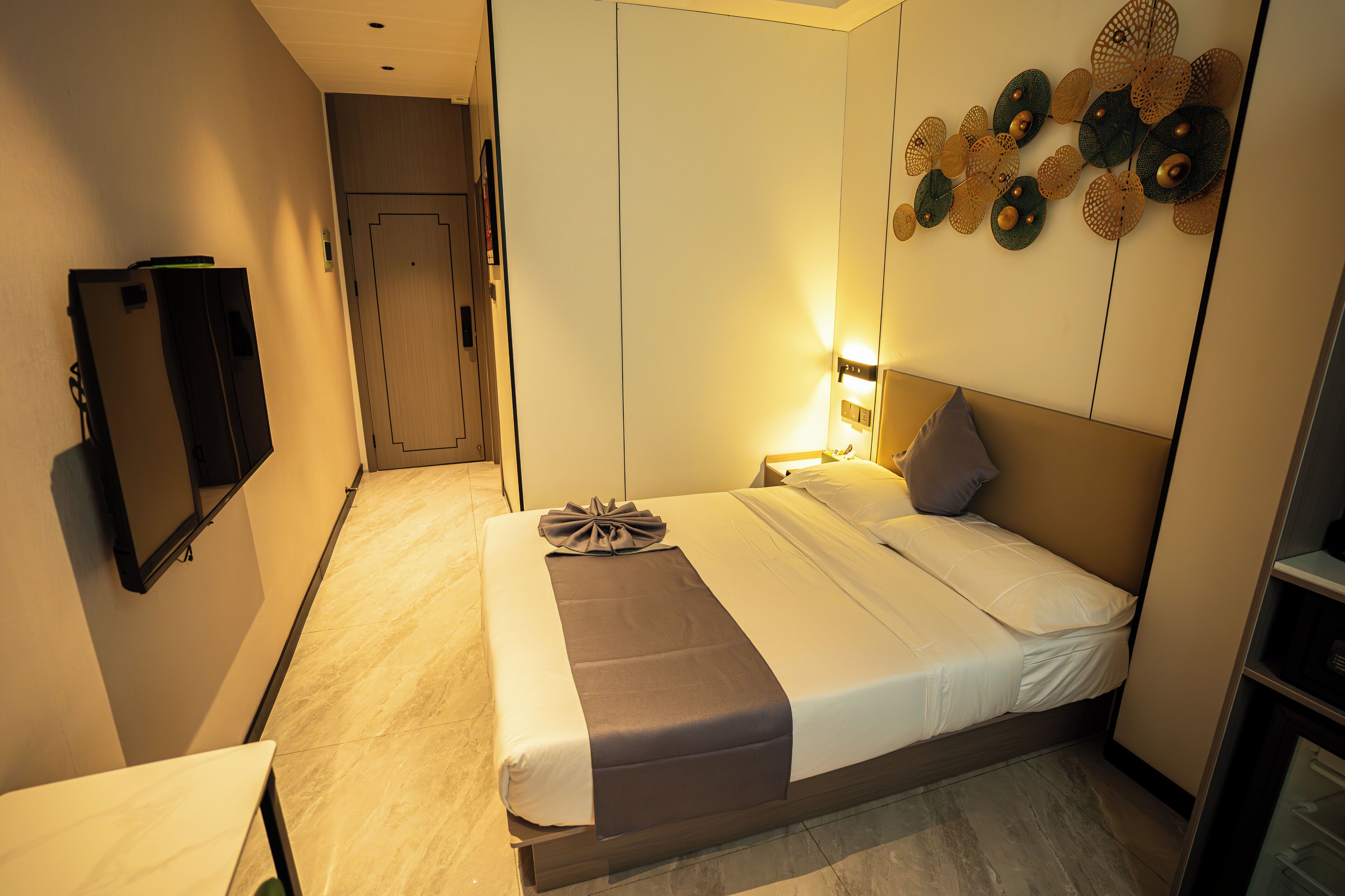 Habitación de hotel con cama, mesita de noche, televisión montada en la pared y decoración mural.