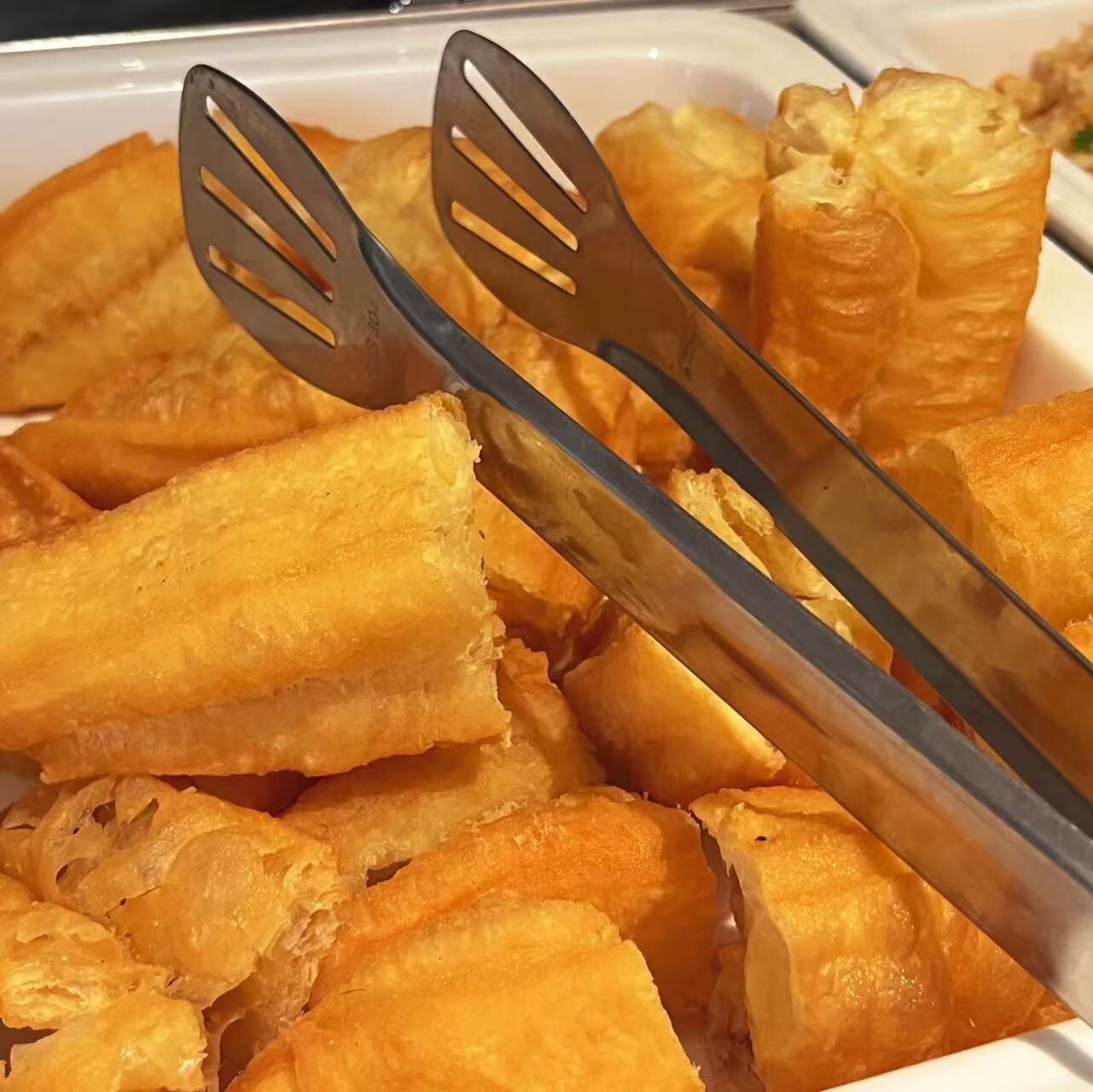 Una bandeja de pasteles dorados con dos espátulas metálicas encima.