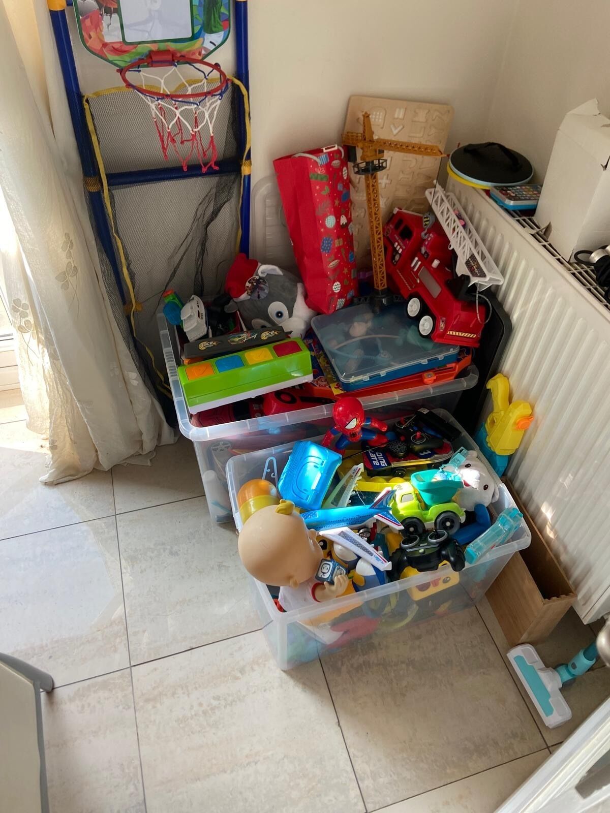 A storage area with various toys and items, including a basketball hoop, a toy fire truck, and a doll.