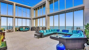 A spacious outdoor lounge area with large windows, a seating arrangement including a sofa and chairs, and a view of the ocean. - Miami Brickell Condos (Miami)