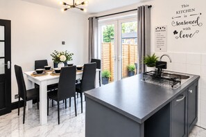 Una cocina moderna con una isla central, mesa de comedor, sillas y vistas al exterior.