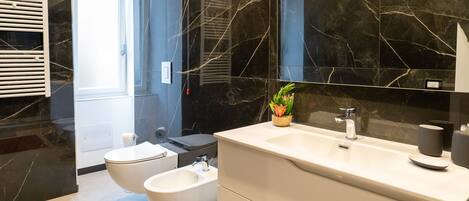 A modern bathroom with a white sink, bidet, and large mirror.