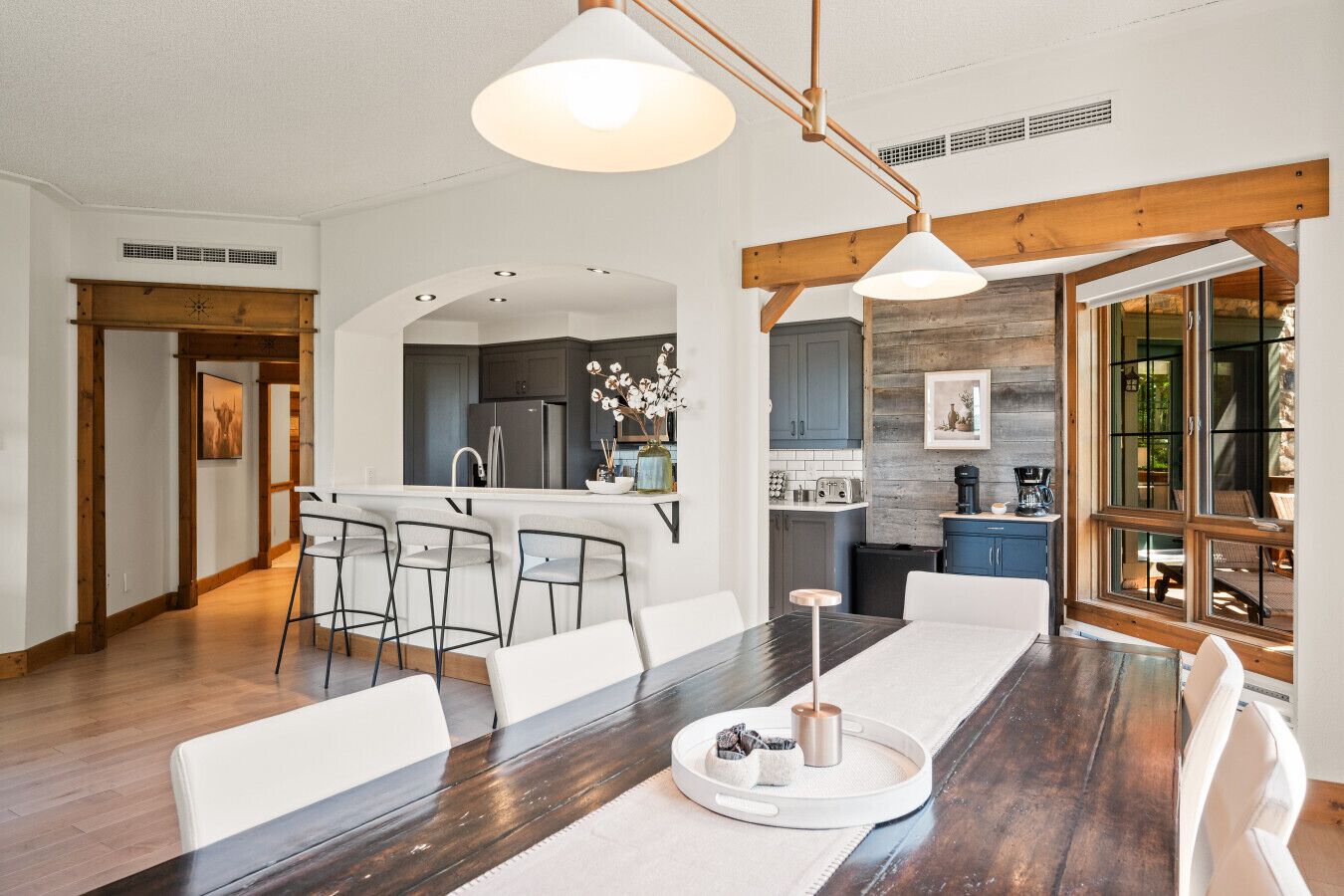 A modern kitchen with a central island, bar stools, and pendant lighting.