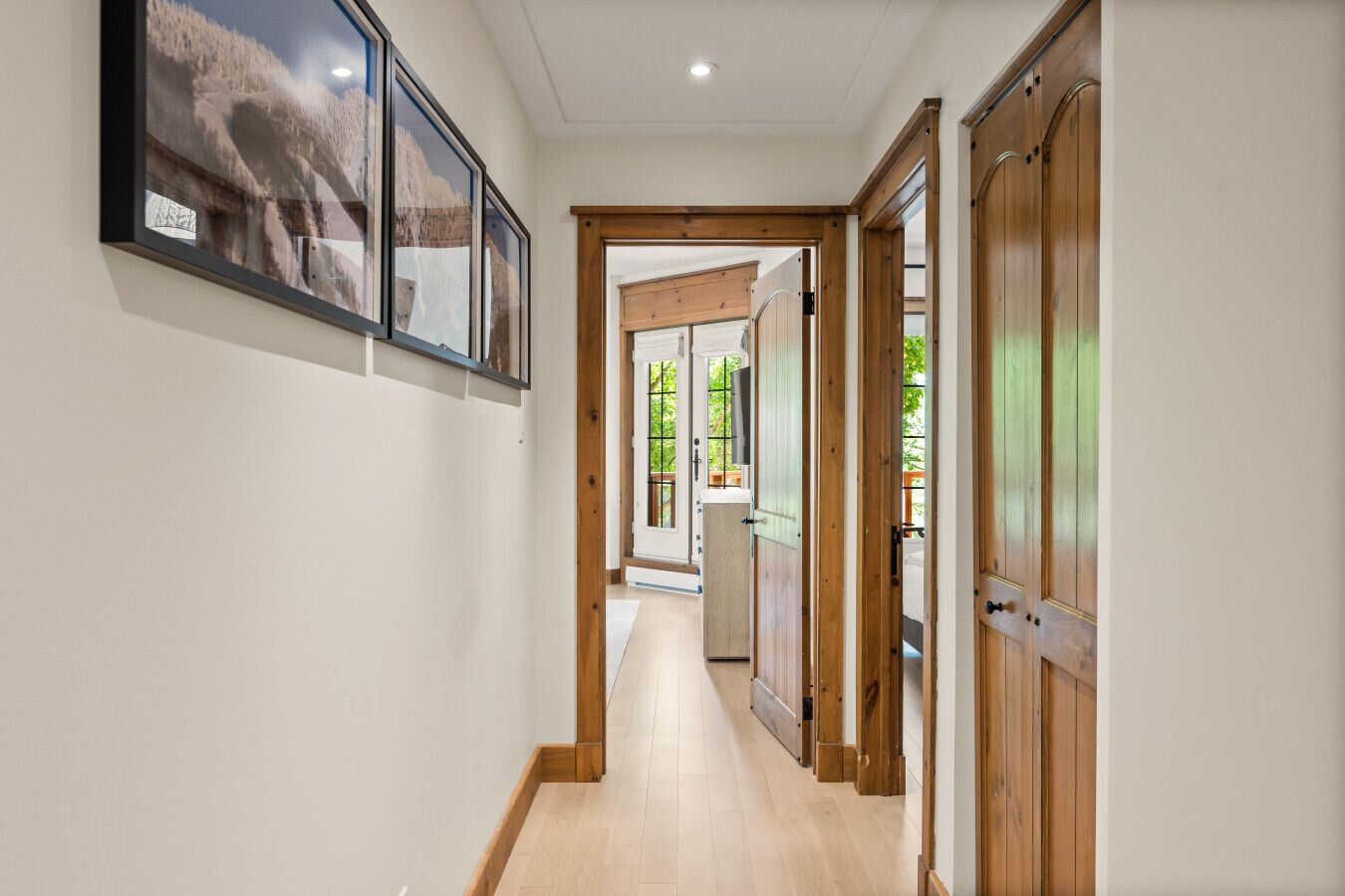 Ein Korridor mit Holztüren, Holzboden und gerahmten Bildern an der Wand.