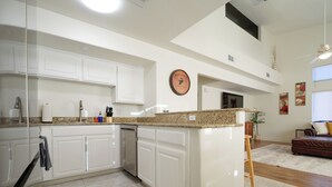 A spacious kitchen with white cabinetry, a granite countertop, and a dishwasher. - 19th Hole at Hawk Ridge (Mesquite)