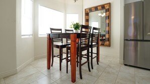 A dining area with a wooden table and chairs, a chandelier, a large mirror, and a stainless steel refrigerator. - 19th Hole at Hawk Ridge (Mesquite)