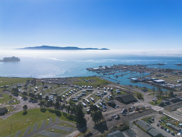 An aerial view of a marina with boats, a parking lot, and a train track. - Roam Tillamook (Garibaldi)