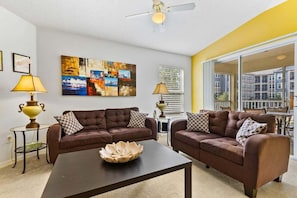 A living room with two brown sofas, a coffee table, and a ceiling fan.