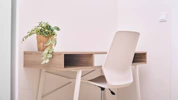 Un espacio de trabajo con una silla blanca, un escritorio de madera y una planta en maceta.