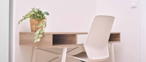 A workspace with a white chair, a wooden desk, and a potted plant.