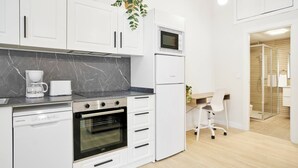 A modern kitchen with white cabinets, a built-in oven, a microwave, and a coffee maker.