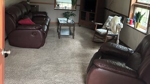 Una sala de estar con un sofá de cuero marrón, una mesa de centro de madera y un televisor sobre un mueble de madera.