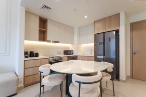 Una cocina moderna con una mesa de comedor redonda, electrodomésticos integrados y un armario de madera.