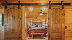A wooden interior with a bed, bench, and ceiling fan.