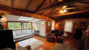 A cozy cabin interior with a living room, a fireplace, and a dining area. - Charming Cabin 500 feet to beach (Plymouth)