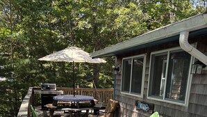 A deck with outdoor furniture, a grill, and a sign indicating a beach view. - Charming Cabin 500 feet to beach (Plymouth)