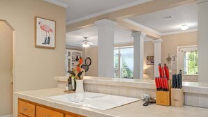 A kitchen with a white countertop, wooden cabinets, and a view to the dining area. - Guadalupe Riverfront Retreat | Sleeps 10 Kerrville (Kerrville)