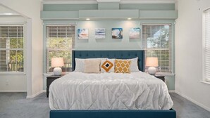 A bedroom with a bed, two bedside lamps, a headboard, and four wall-mounted pictures. - Guadalupe Riverfront Retreat | Sleeps 10 Kerrville (Kerrville)