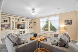 A living room with a sofa set, a coffee table, a television, and a window with curtains. - Guadalupe Riverfront Retreat | Sleeps 10 Kerrville (Kerrville)