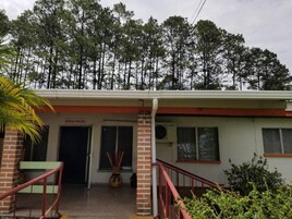 Um edifício com telhado vermelho, entrada de tijolos e uma placa com a inscrição 'ENTRADA PRINCIPAL'.