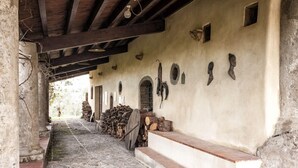 A corridor with a stone floor, wooden beams, and a wall with arched doorways and wall-mounted objects.