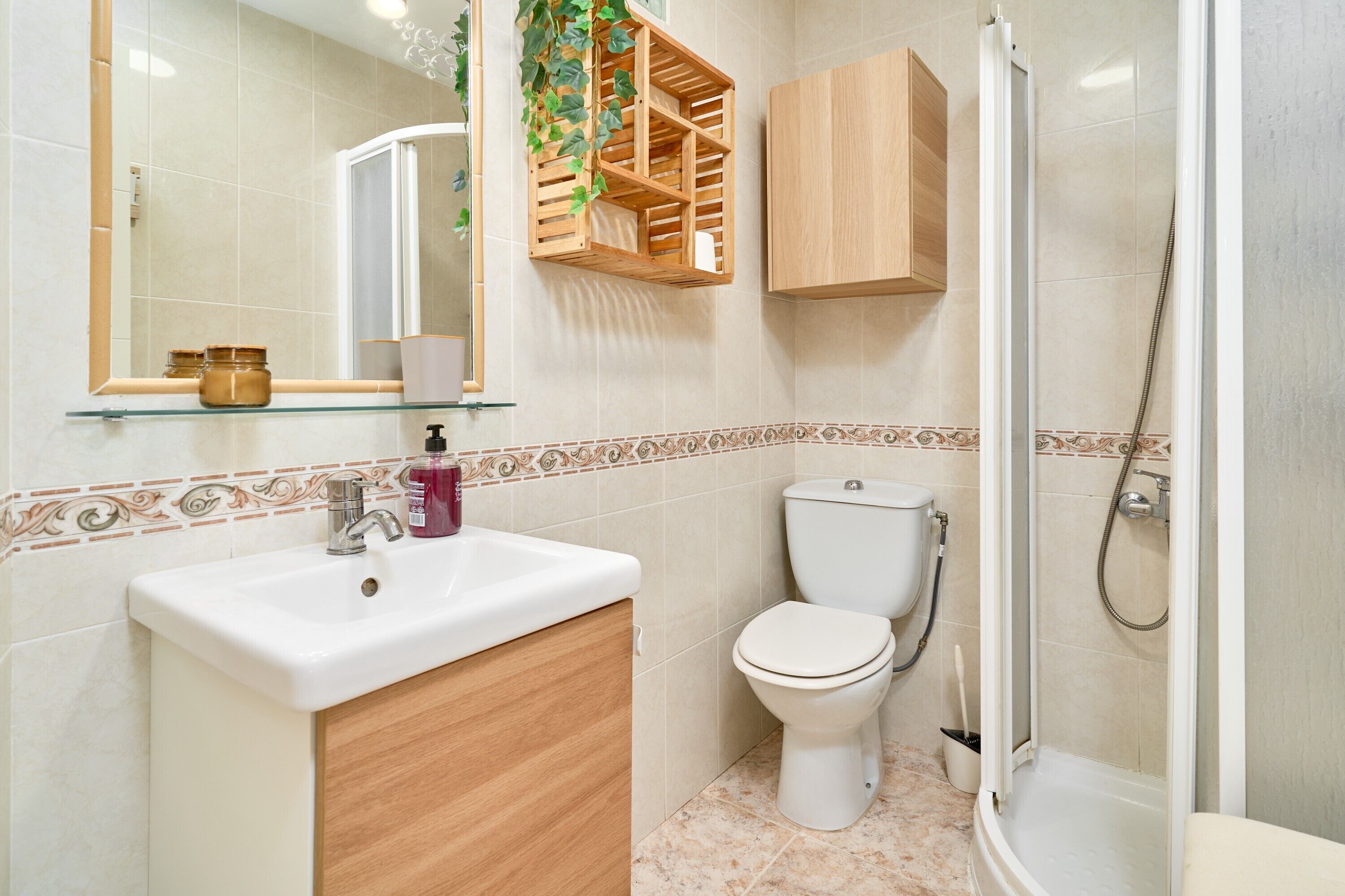 Une salle de bain avec un lavabo en verre, un meuble en bois, des toilettes et un espace douche.