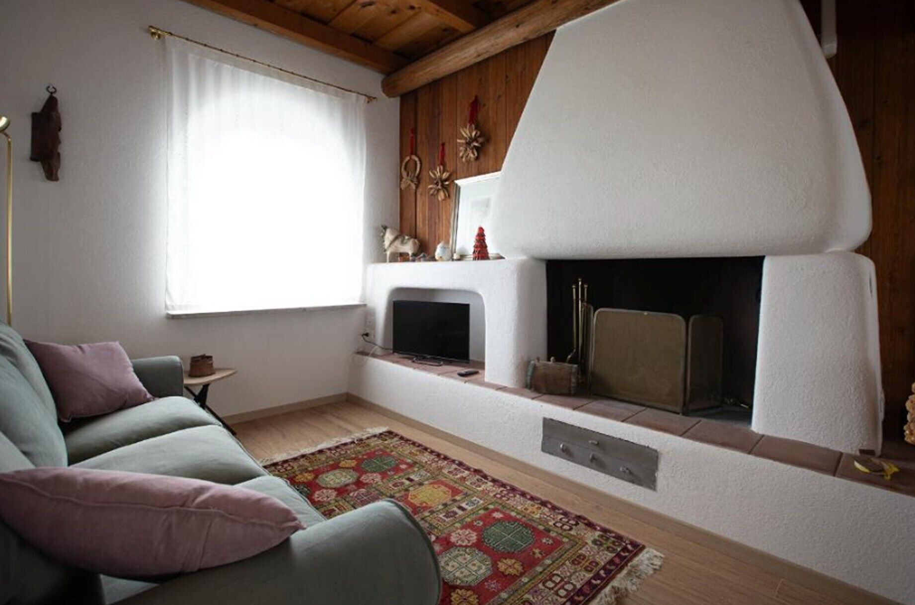 A living room with a sofa, a fireplace, a television, and a window with curtains.