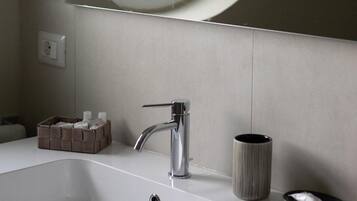 Un bany amb un lavabo blanc, un mirall rodó i una finestra.