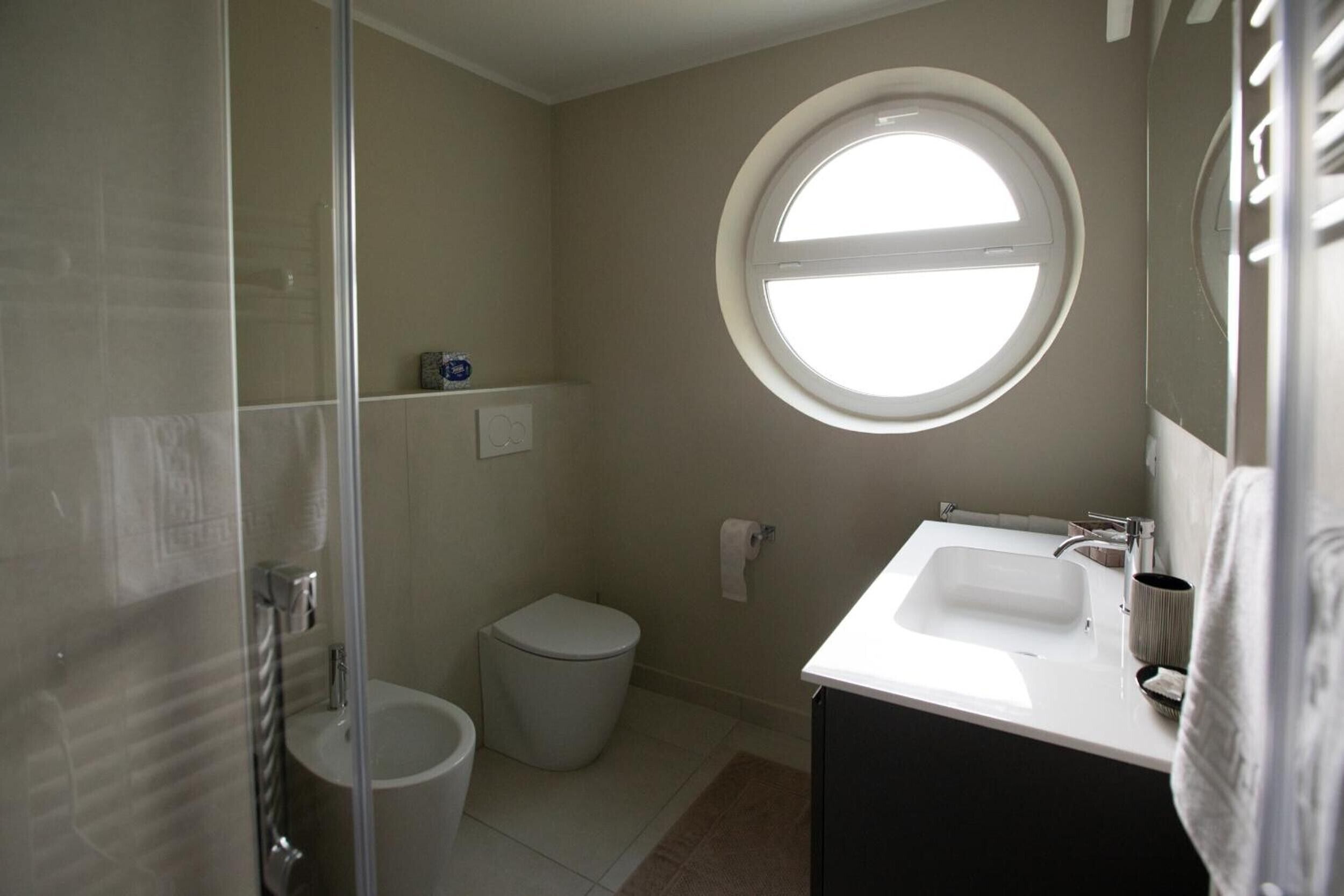 Une salle de bain avec des toilettes, un lavabo et une fenêtre.