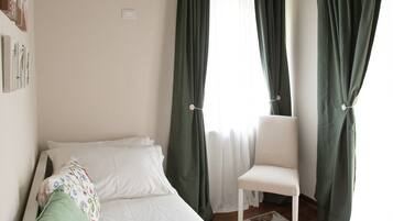 Ein Schlafzimmer mit einem Bett, einem Sessel und Vorhängen.