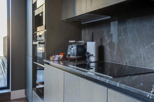 Una cocina moderna con encimera negra elegante, electrodomésticos de acero inoxidable y un amplio ventanal que proporciona luz natural.