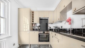 A modern kitchen with built-in appliances, a central oven, and a window providing natural light. - A Scholar s Gallery - Bloomsbury - by Frankie Says (London)