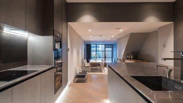 A modern kitchen with a central island, built-in appliances, and a view to the dining area. - Monochrome Majesty - Soho - by Frankie Says (London)
