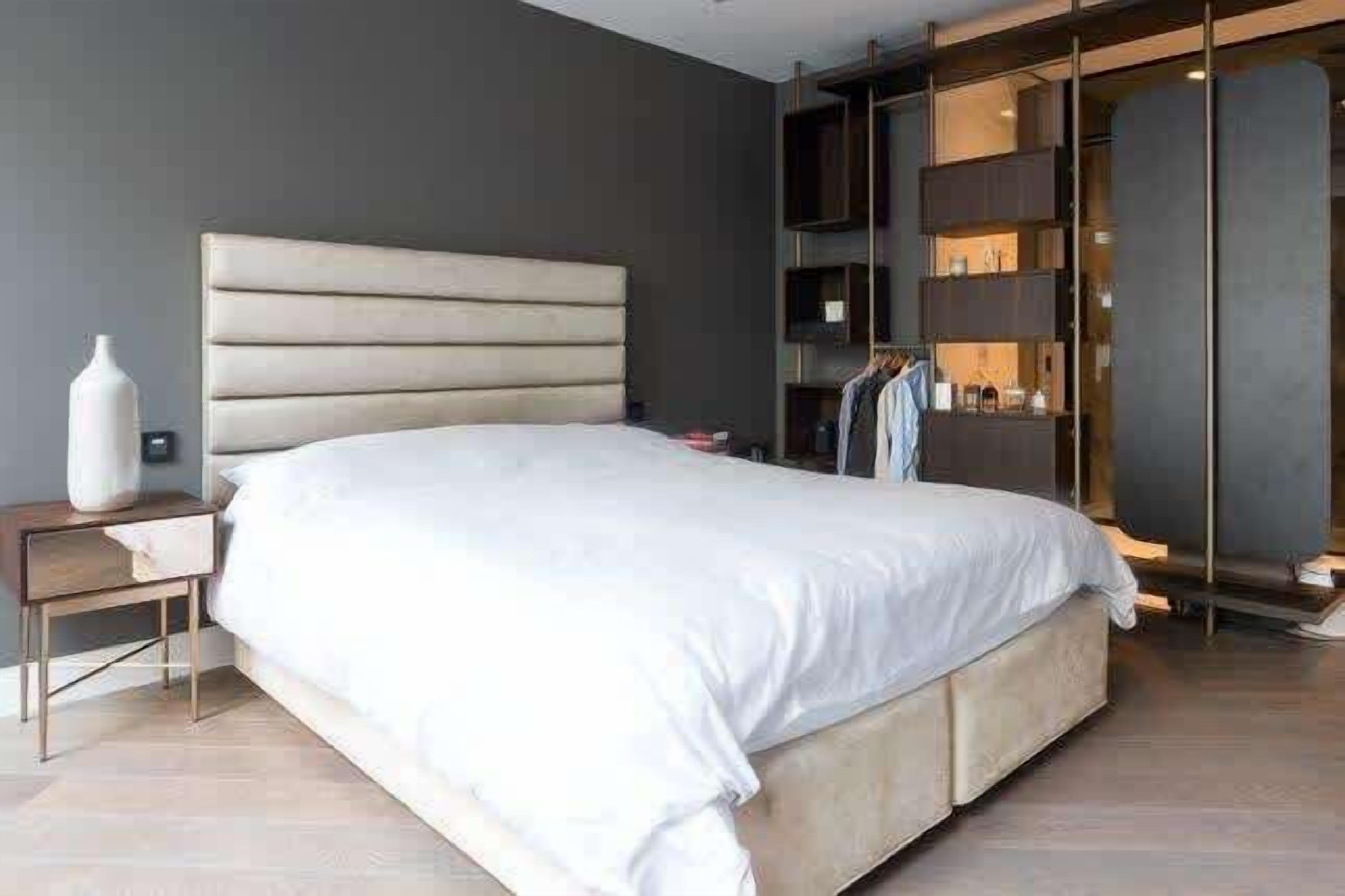 Une chambre moderne avec un grand lit, une table de chevet et une armoire intégrée.