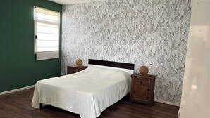 Una camera da letto con un letto, comodini, una finestra e carta da parati decorata.