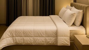 A modern bedroom with a large bed, a nightstand, and a wooden floor. - Pyramids heavin inn (Giza)