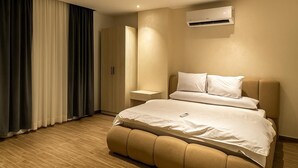 A modern hotel room with a large bed, a bedside table, an air conditioning unit, and a wardrobe. - Pyramids heavin inn (Giza)