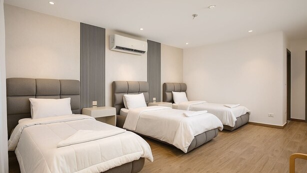 A hotel room with three beds, a modern air conditioning unit, and a wooden floor. - Pyramids heavin inn (Giza)