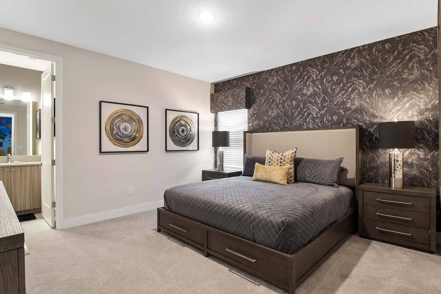 A bedroom with a large bed, two bedside tables, a nightstand, and two wall-mounted lamps.