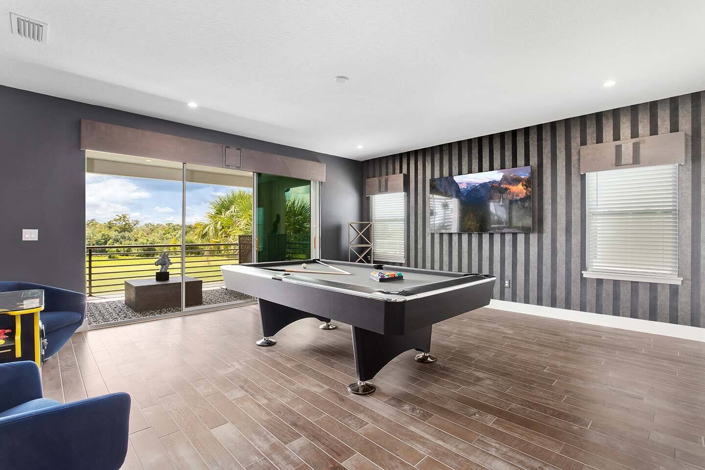 A modern indoor pool table with a clear view of the outdoors through large windows.